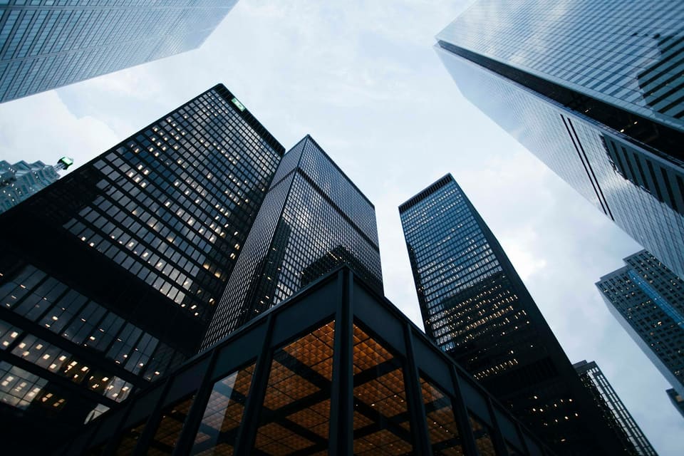 Glass and steel office towers photographed from street level against a pale sky.