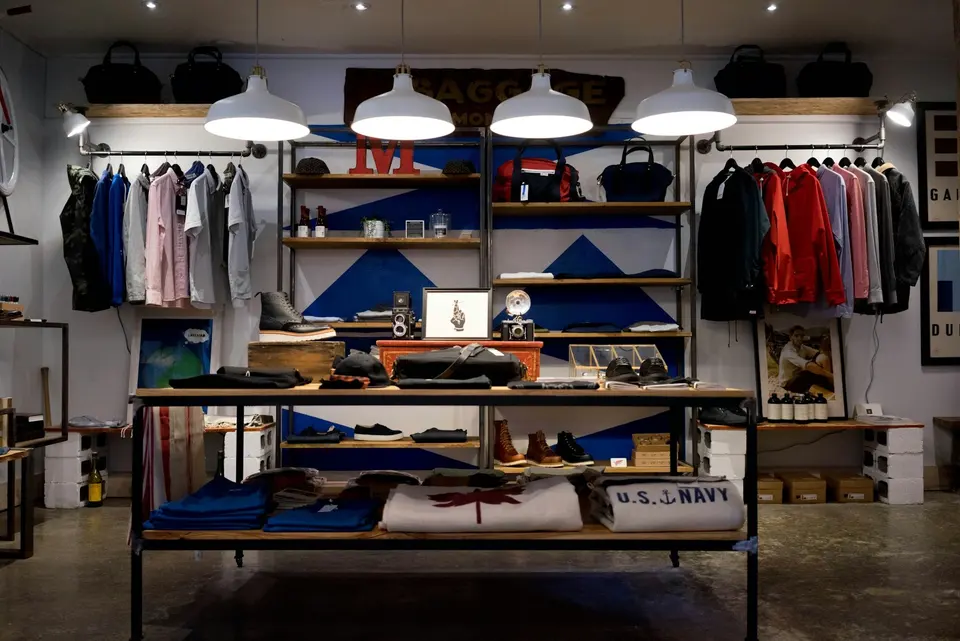 Clothing, bags and accessories displayed on open shelving and rails in a small shop.